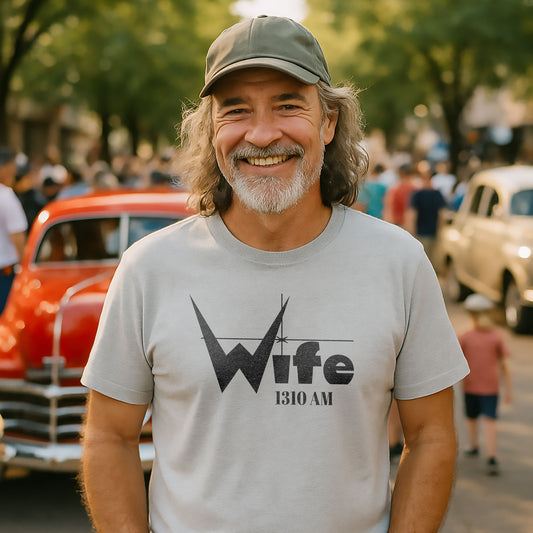Smiling man wearing a vintage WIFE 1310 AM Indianapolis radio nostalgia t-shirt at a classic car gathering.