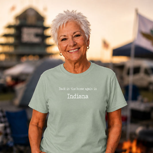 Older woman wearing a mint green “Back in the Home Again in Indiana” funny Hoosier humor t-shirt while camping outside the Indianapolis Motor Speedway at sunset.