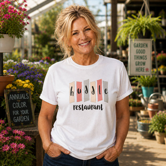 Middle-aged woman wearing a vintage Huddle Restaurant Indianapolis nostalgia shirt at a sunny spring garden center