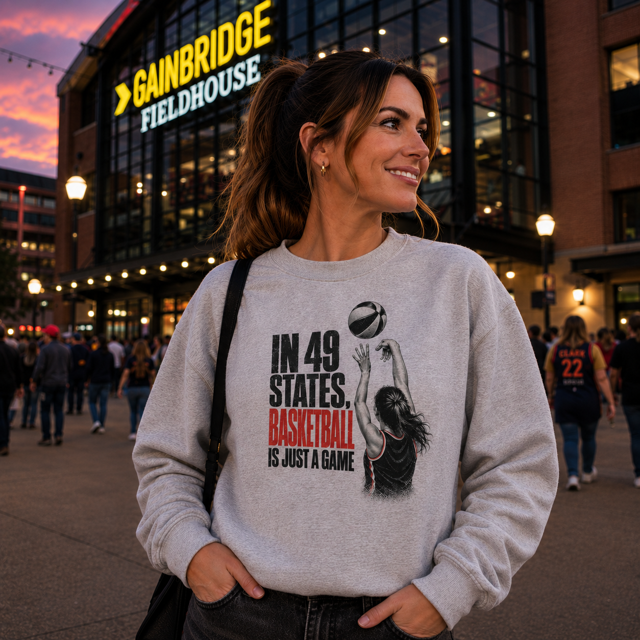 Woman wearing an Indiana basketball Gildan 18000 sweatshirt featuring the In 49 States Basketball Is Just a Game design outside an Indiana basketball arena.