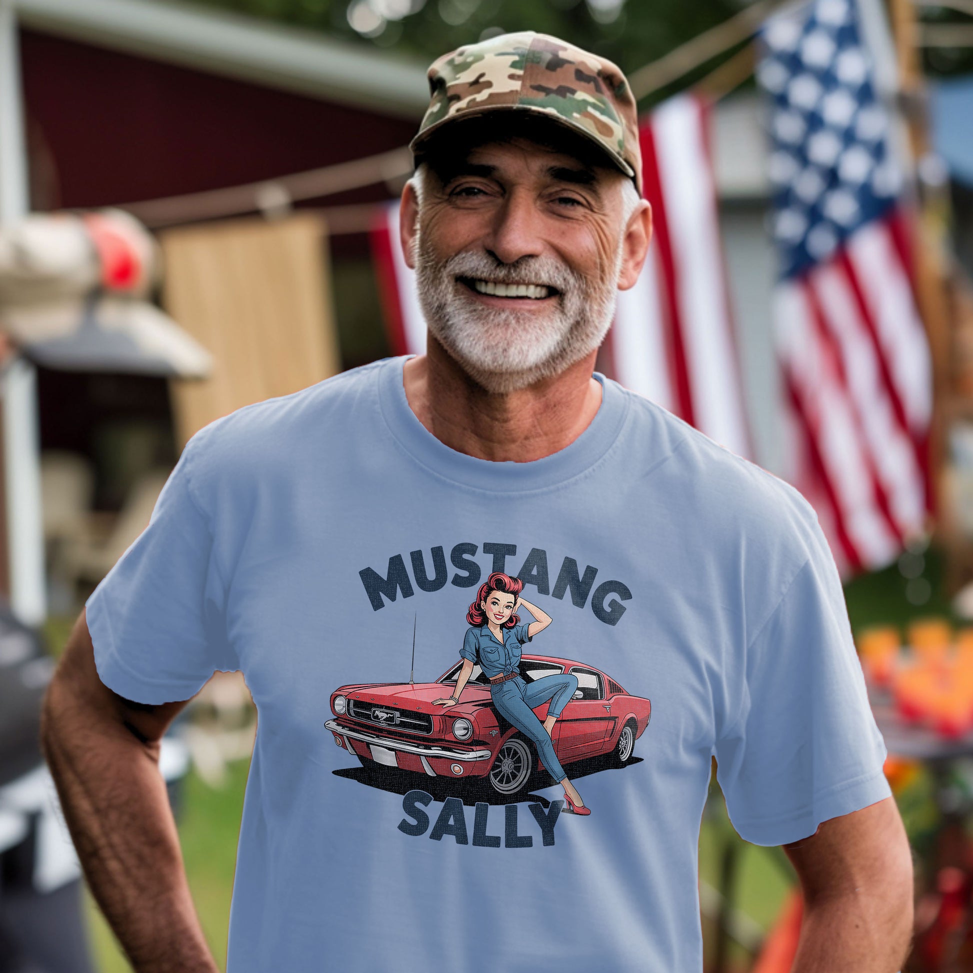 Smiling man wearing Mustang Sally muscle car t-shirt outdoors with American flag in background