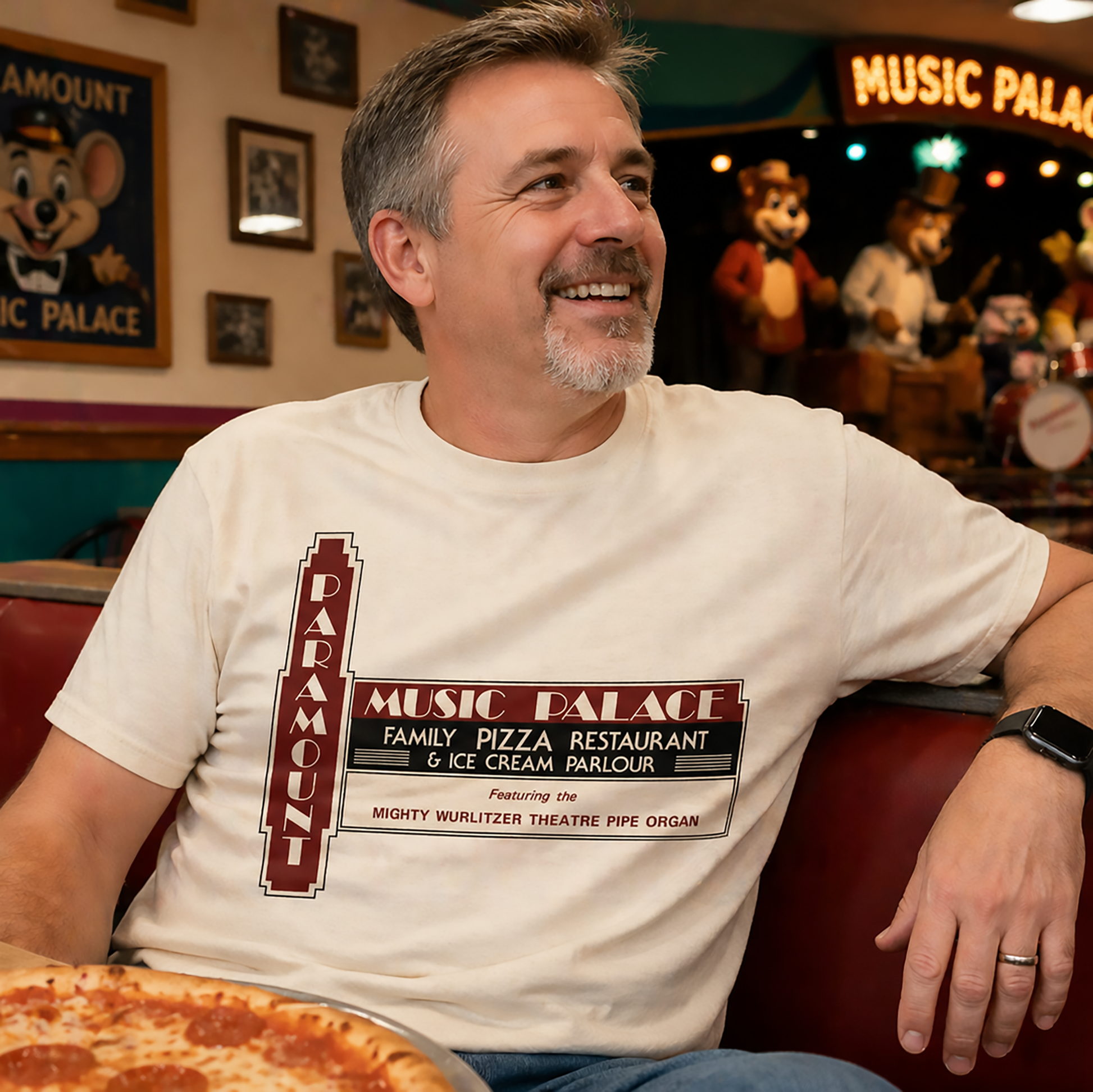 Middle-aged man wearing Paramount Music Palace shirt sitting in casual pizza restaurant setting

