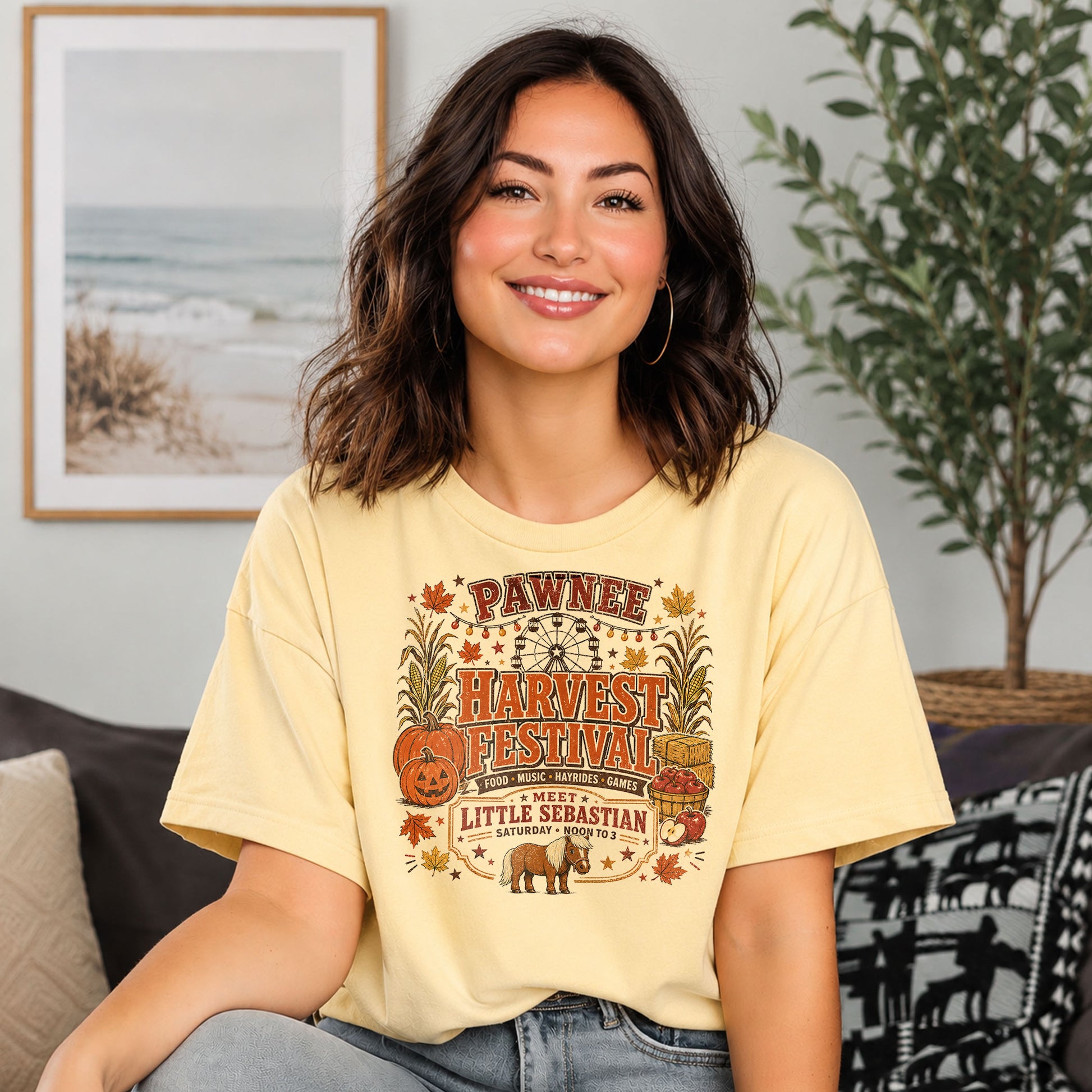 Woman wearing a Pawnee Harvest Festival Indiana-inspired Comfort Colors t-shirt featuring pumpkins, carnival rides, autumn decorations, and Little Sebastian.