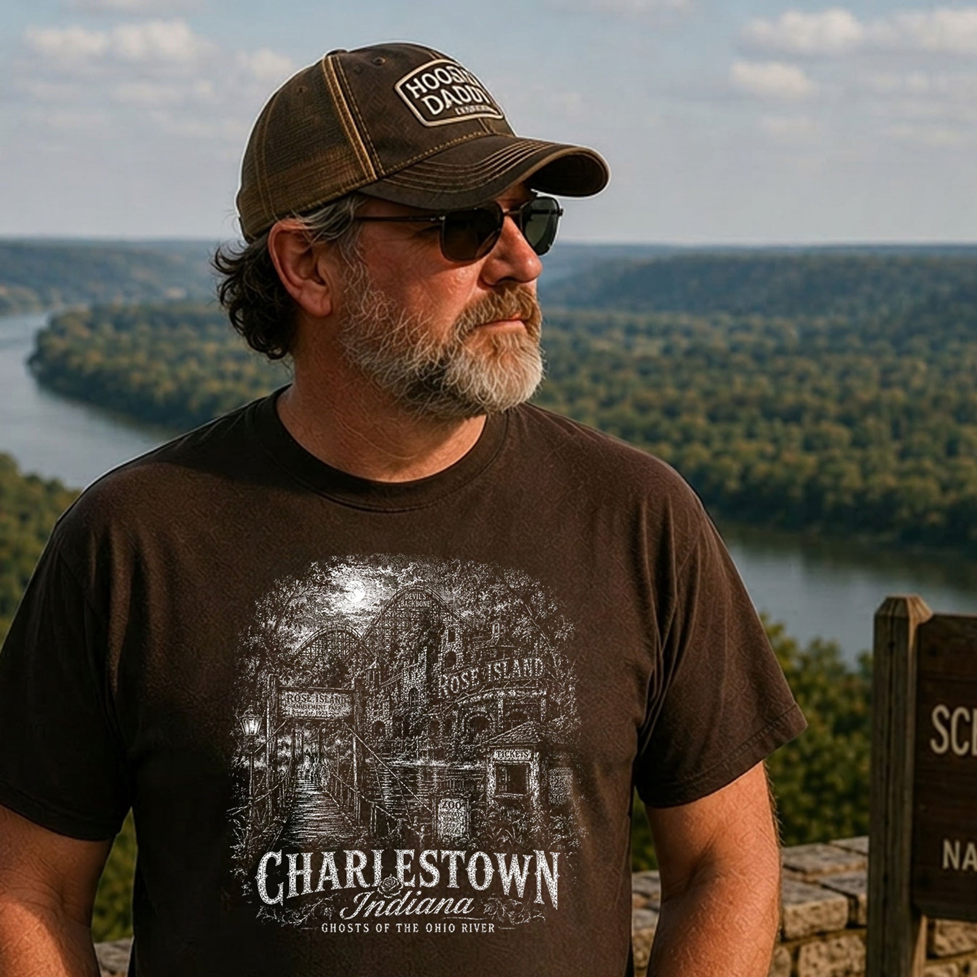 Older man standing at an Indiana scenic overlook wearing a chocolate brown t-shirt featuring a vintage engraved illustration of the Tulip Trestle railroad bridge in Greene County, Indiana.