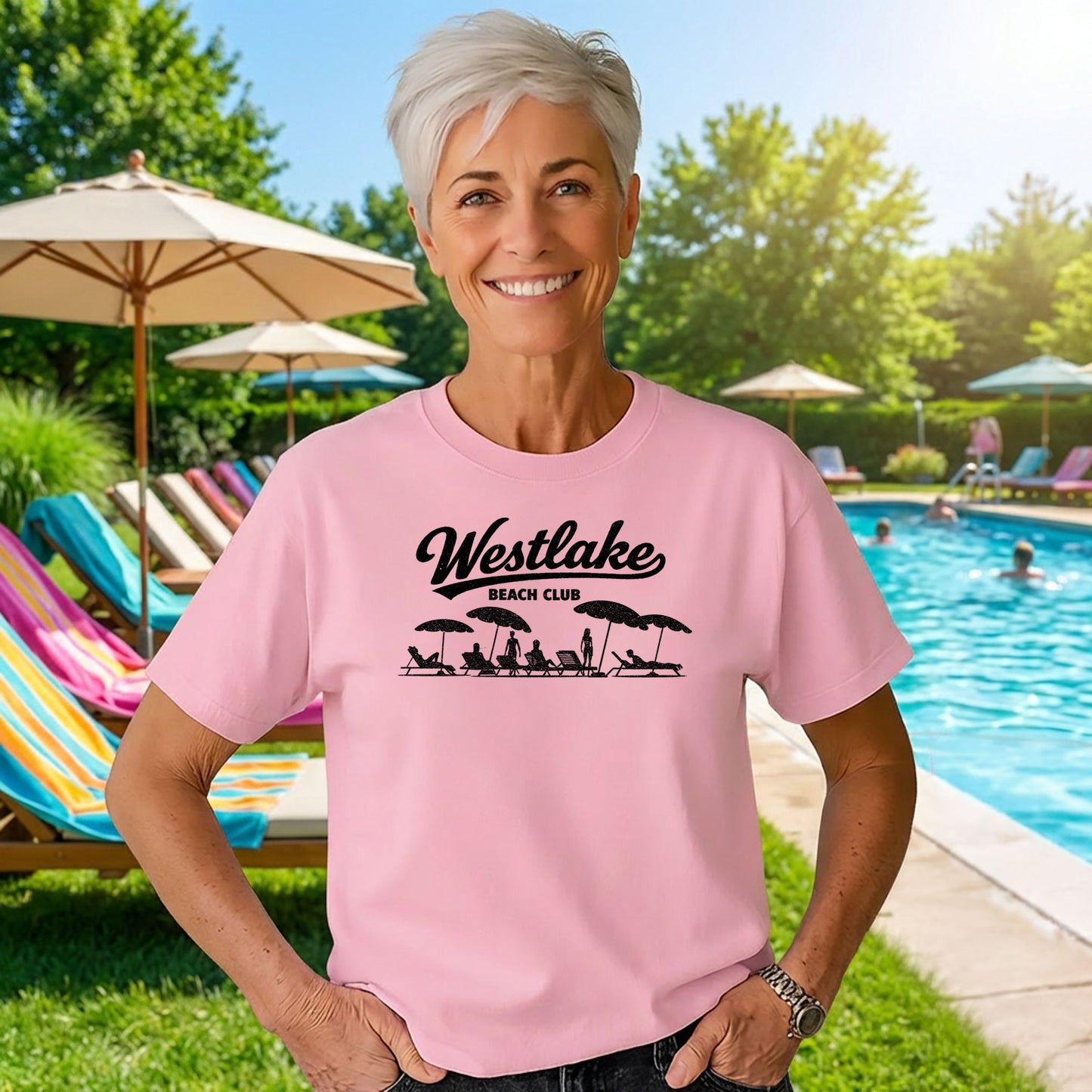 Woman wearing pink Westlake Beach Club t shirt standing by outdoor pool on sunny day
