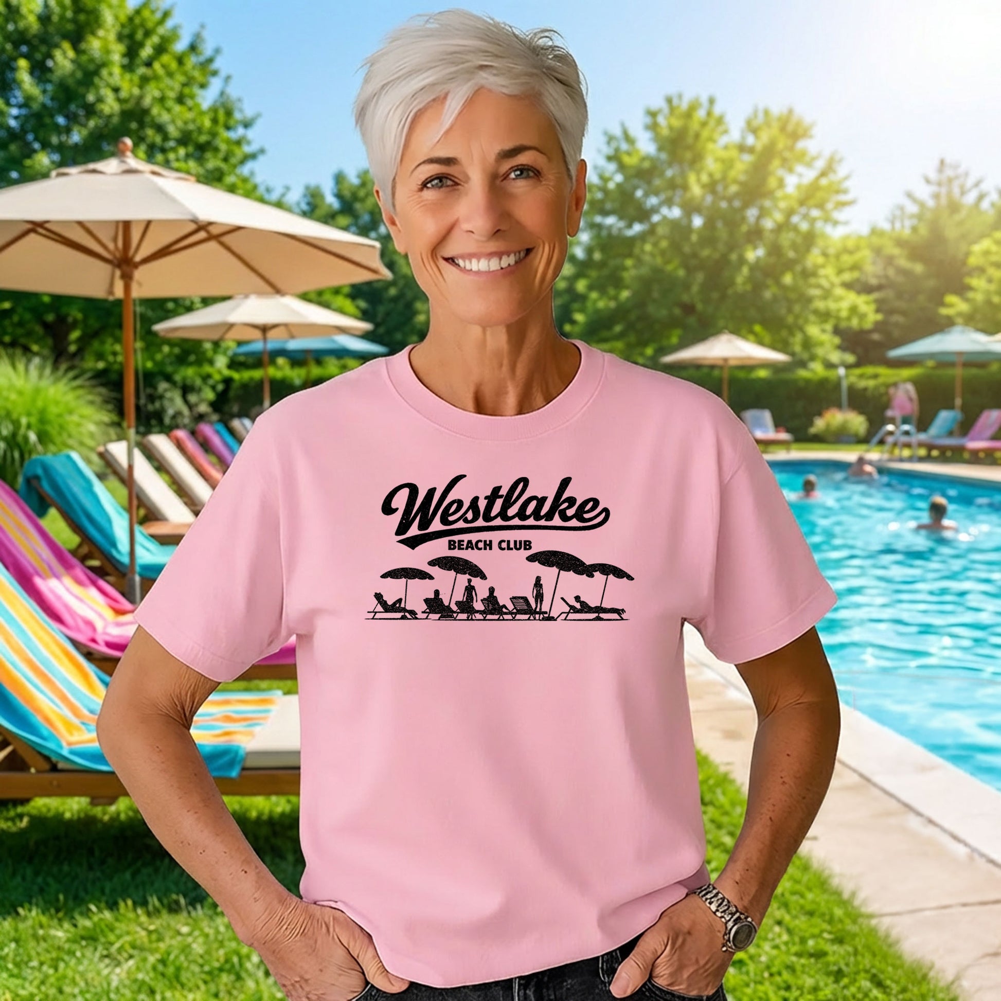 Woman wearing pink Westlake Beach Club t shirt standing by outdoor pool on sunny day